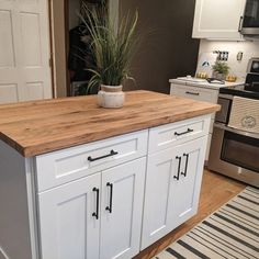 a kitchen island with a potted plant sitting on it's top in front of an oven