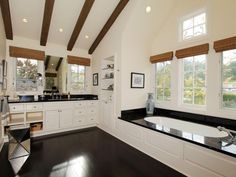 a large bathroom with white cabinets and black counter tops, along with a deep soaking tub