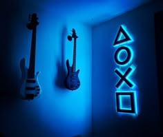 two guitars are lit up against the wall next to a neon sign that says xbox