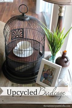 an upcycled birdcage is sitting on a table next to a lamp