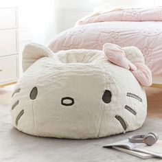 a white cat shaped bed sitting on top of a floor next to a pink comforter