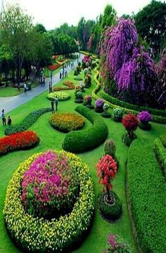 people are walking in the middle of a flower garden