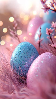 three blue and pink easter eggs sitting on top of a grass covered field with flowers