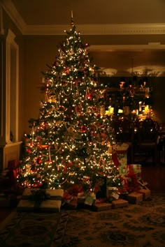 a lit christmas tree with presents under it