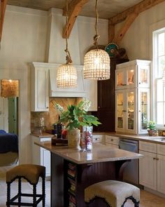 a kitchen with two lights hanging from the ceiling and stools in front of it