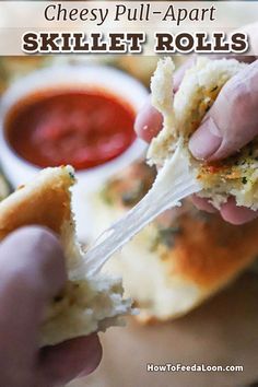 a person holding a piece of bread with sauce in the background