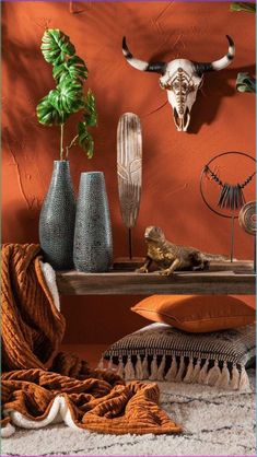 two vases with long horns are sitting on a shelf in front of an orange wall