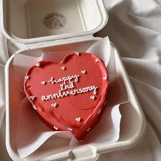 a heart shaped cake in a box with writing on the side and hearts around it