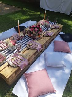 a table set up with pink napkins and place settings for dinner on the grass