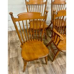 three wooden chairs sitting next to each other on top of a hard wood floored floor