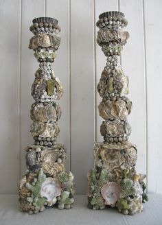 two tall vases with shells and seashells on them sitting next to each other