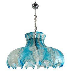 a blue glass chandelier hanging from a metal chain on an isolated white background