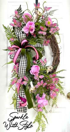 a wreath with pink flowers and greenery hanging on the front door to welcome guests