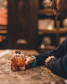 a man sitting at a bar with a drink in front of him and looking off into the distance