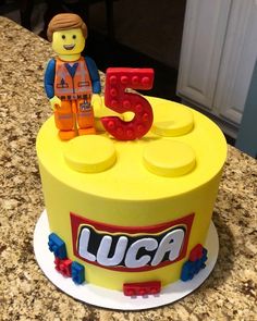 a lego themed birthday cake with the number five on it's front and an image of a man in construction gear on top