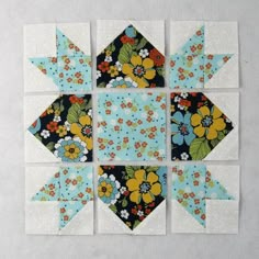 four blocks are arranged in the shape of an origami flower and one block is made out of paper