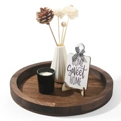 a small vase with flowers and a sign on a wooden tray that says home sweet home