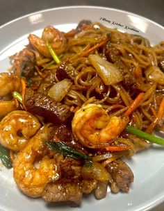 a white plate topped with noodles and shrimp