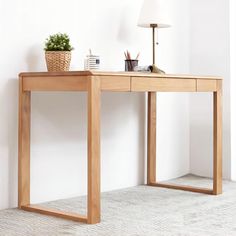 a wooden desk with a lamp on top and a potted plant next to it