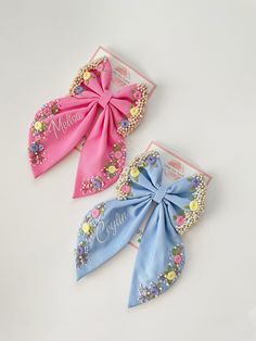 two pink and blue bows with flowers on them are sitting next to each other in front of a white background