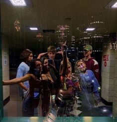 a group of people standing in front of a window with their hands up to the sky