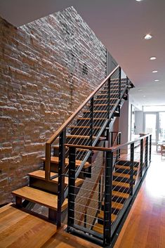 a stair case in front of a brick wall and wooden floors with metal handrails