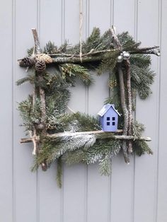 a small blue house sitting on top of a pine tree branch frame made out of branches