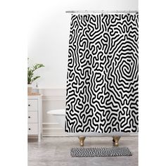 a black and white shower curtain with an abstract design on the side, in front of a bathtub