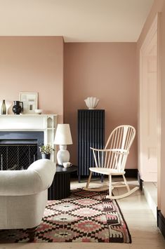 a living room filled with furniture and a fire place next to a white chair on top of a rug