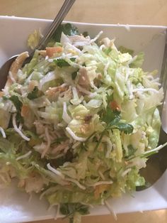 a salad in a white bowl with a fork and spoon on the side, ready to be eaten