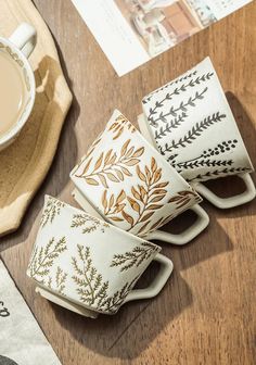 four coffee cups sitting on top of a wooden table