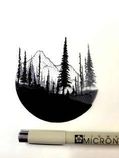 a pen sitting next to a drawing of trees and mountains on a white surface with the word microfit written in black ink