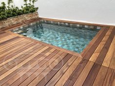 a wooden deck next to a swimming pool with glass tiles on the bottom and sides