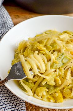 a white bowl filled with pasta and broccoli on top of a wooden table