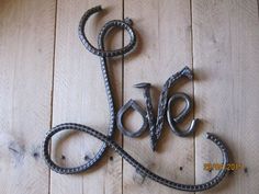 the word love is made out of metal wire on a wooden floor with wood planks