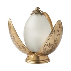 an egg sitting on top of a golden stand with a white ball in the middle