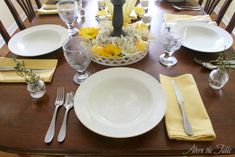 a table set with plates, silverware and yellow napkins on top of it