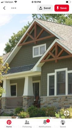 a house with stone and wood trim on the front porch, covered in shingles