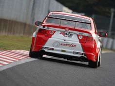 a red and white car driving down a race track