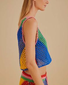 a woman wearing a multicolored crochet crop top and matching shorts is standing in front of a beige background