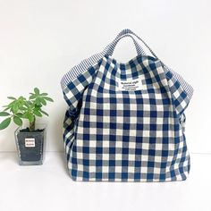 a blue and white checkered bag next to a potted plant