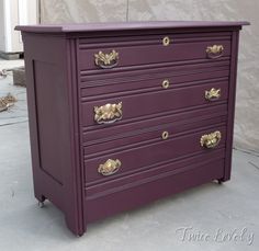 a purple dresser with gold handles on it's top and bottom drawers, against a white background