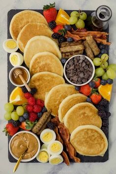 pancakes, fruit, and other foods are arranged on a platter to be eaten