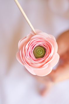 a person holding a flower made out of rolled up paper with a stick in their hand