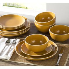 a table set with yellow dishes and silverware