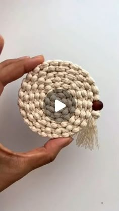 someone is holding up a small crocheted object with a video playing button on it