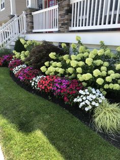 a flower bed in front of a house with grass and flowers growing on the side