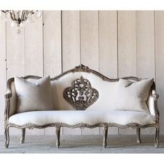 a white couch sitting in front of a wooden wall with a chandelier hanging from the ceiling