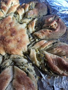 baked bread with spinach and cheese on aluminum foil lined up in the shape of flowers