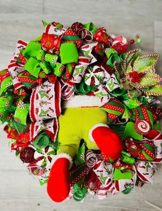 a christmas wreath with green and red decorations on it, sitting on top of a wooden floor